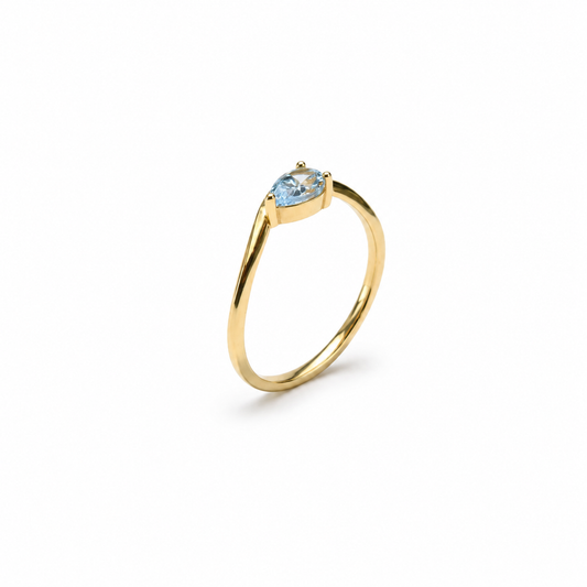 Prsten zlatni 14KT s akvamarinom ističe se profinjenim žutim tonom zlata i nježnim plavim kamenom koji prstenu daje svjež, elegantan i vrlo ženstven izgled. Jednostavna forma obruča lijepo naglašava akvamarin i čini ovaj model decentnim, ali posebnim komadom nakita.